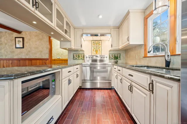 a kitchen with stainless steel appliances white cabinets and wooden floors