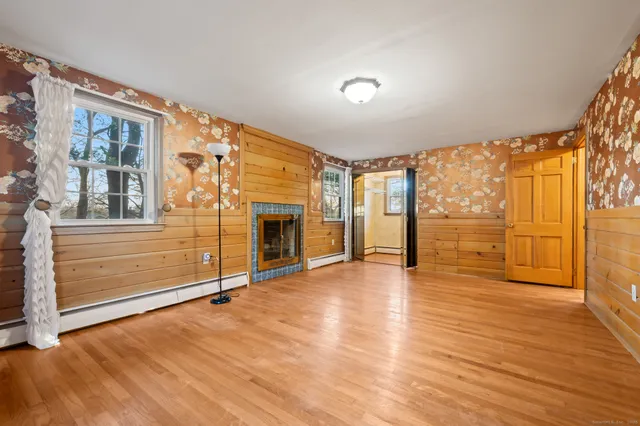 a view of an empty room with wooden floor and fireplace