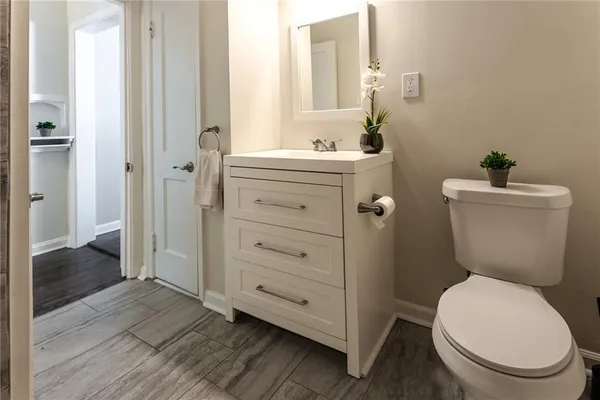 a bathroom with a toilet a sink and wooden floor