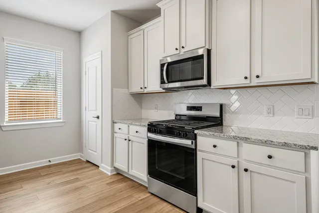 a kitchen with white cabinets and appliances
