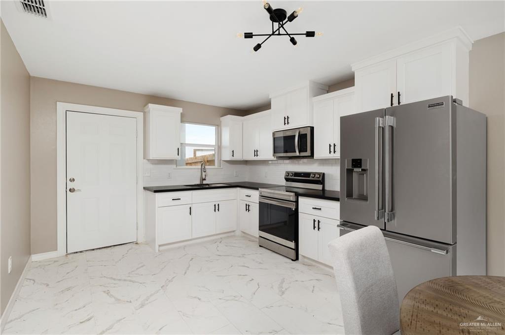 1712 West B Street Mission, TX 78572 - Photo 5 of 11 a kitchen with stainless steel appliances granite countertop a refrigerator a stove top oven a sink and dishwasher