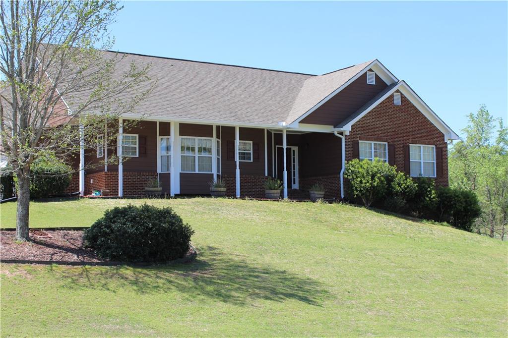 a view of a brick house with a big yard and large trees