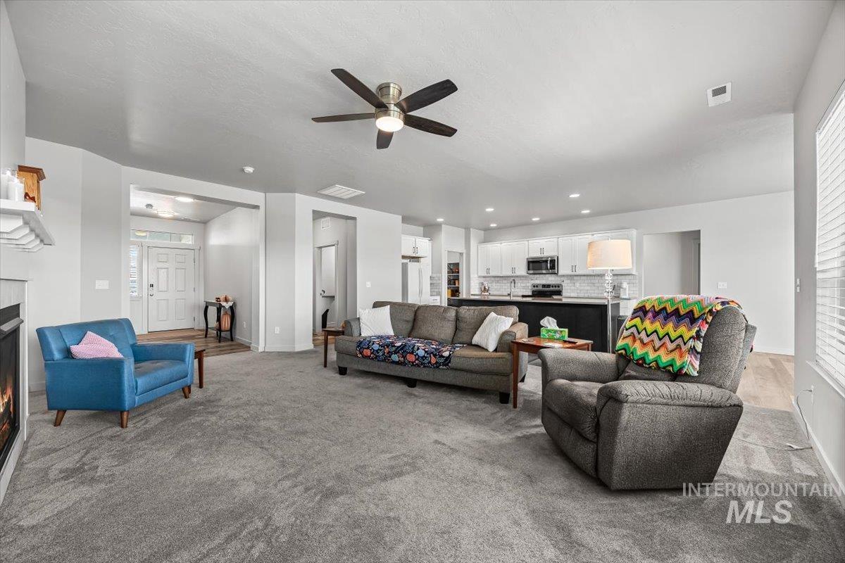 15365 Lutsen Avenue Caldwell, ID 83607 - Photo 14 of 42 Living room with carpet, a warm lit fireplace, a ceiling fan, and recessed lighting