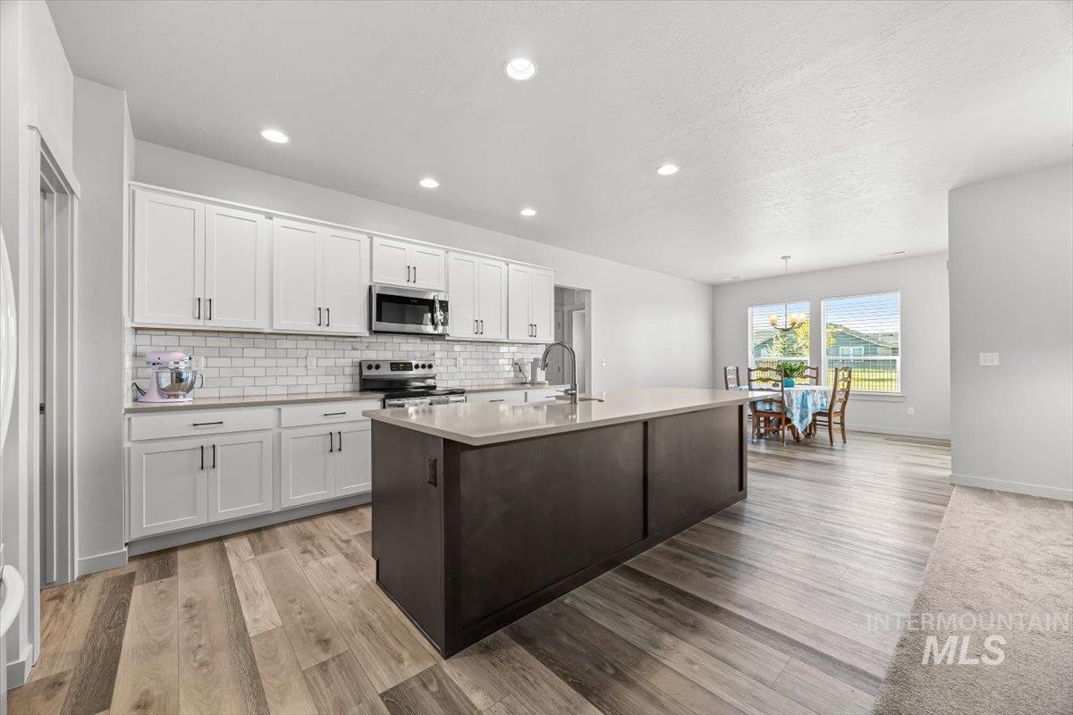 15365 Lutsen Avenue Caldwell, ID 83607 - Photo 17 of 42 Kitchen with white cabinetry, a kitchen island with sink, decorative backsplash, appliances with stainless steel finishes, and recessed lighting