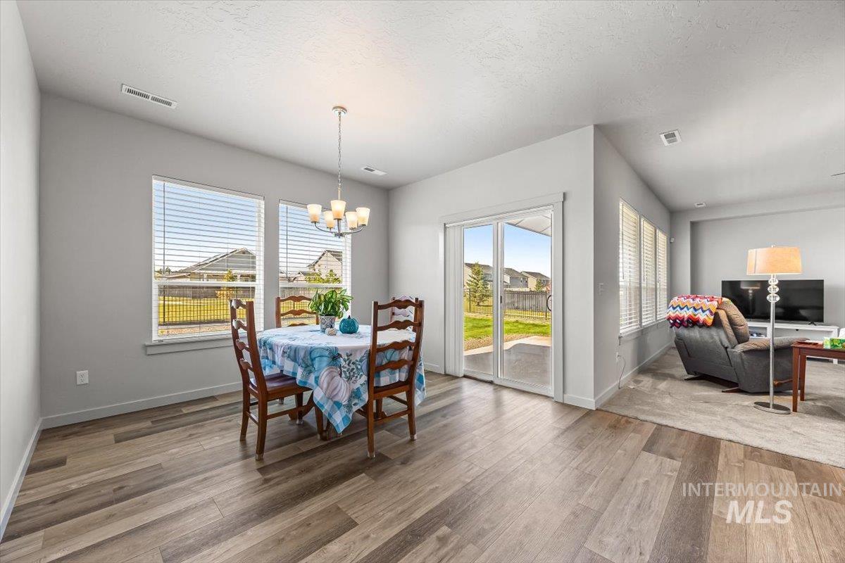 15365 Lutsen Avenue Caldwell, ID 83607 - Photo 18 of 42 Dining area featuring healthy amount of natural light, a textured ceiling, light wood-style floors, and a chandelier