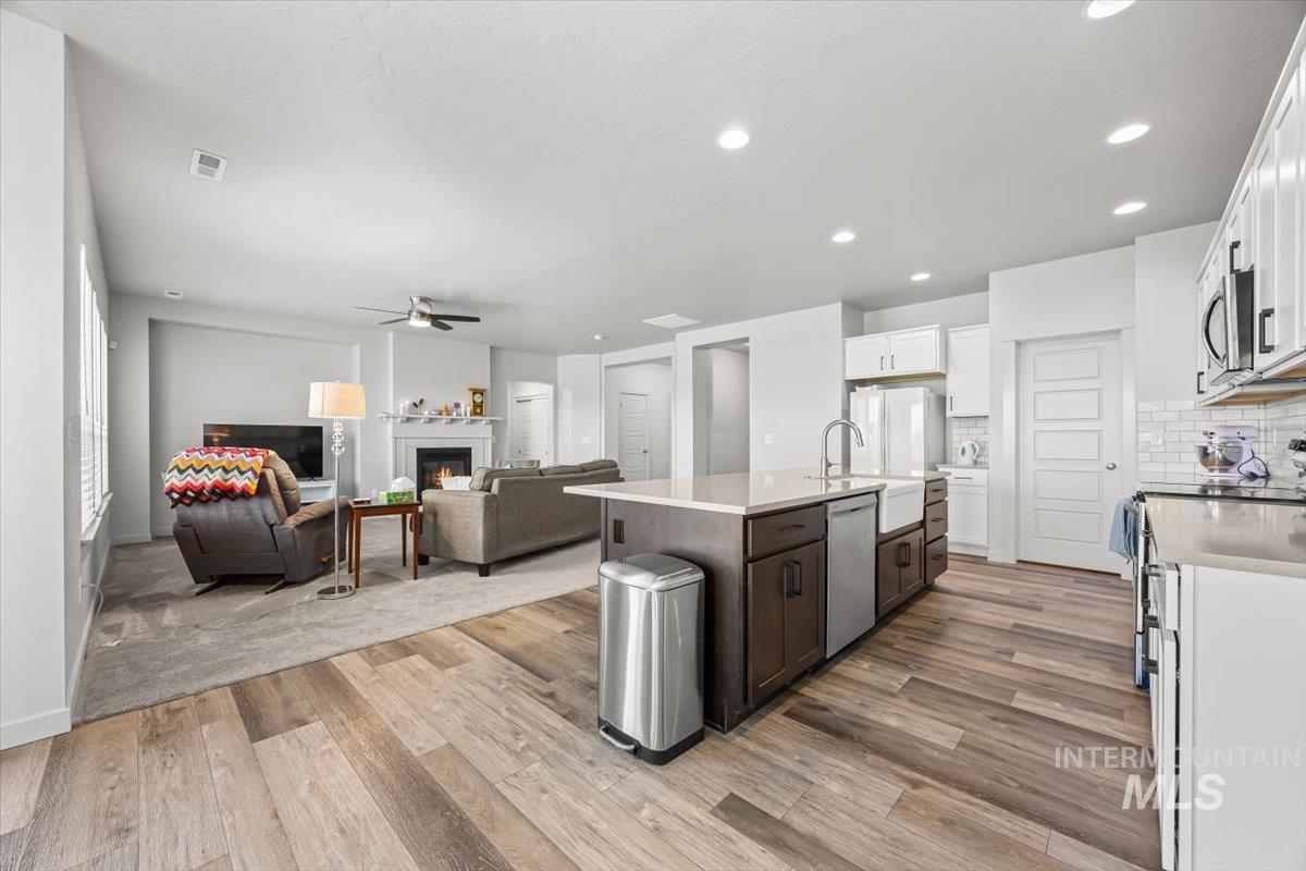 15365 Lutsen Avenue Caldwell, ID 83607 - Photo 42 of 42 Kitchen featuring appliances with stainless steel finishes, a glass covered fireplace, tasteful backsplash, white cabinets, and open floor plan