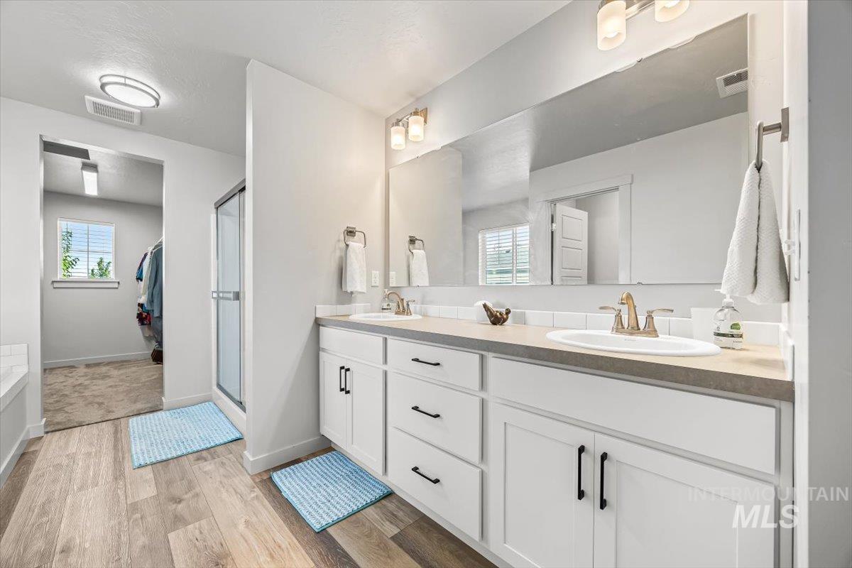 15365 Lutsen Avenue Caldwell, ID 83607 - Photo 28 of 42 Full bathroom featuring double vanity, light wood-style flooring, plenty of natural light, a stall shower, and a textured ceiling