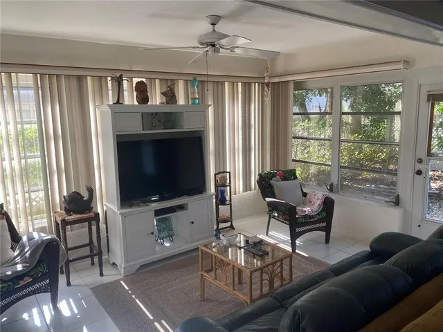 a living room with furniture a flat screen tv and a large window