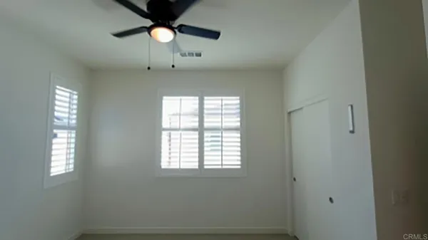 an empty room with windows and fan