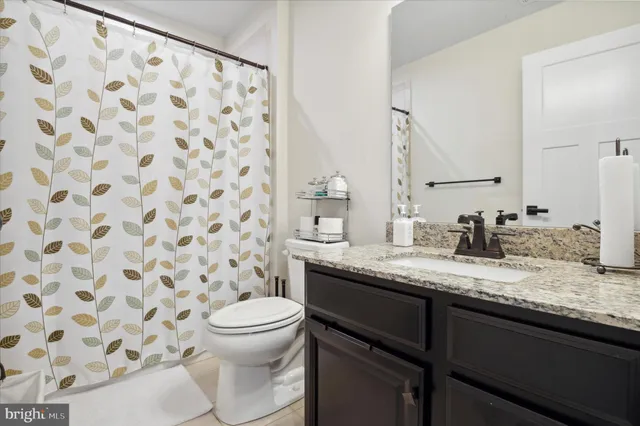 a bathroom with a granite countertop sink a toilet and a mirror