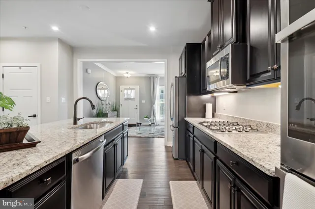 a kitchen with stainless steel appliances granite countertop a sink a stove and a wooden floors