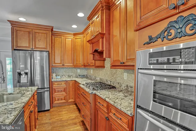 a kitchen with granite countertop lots of wooden furniture and stainless steel appliances
