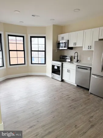 a open kitchen with granite countertop a stove top oven a sink dishwasher and a refrigerator with wooden floor