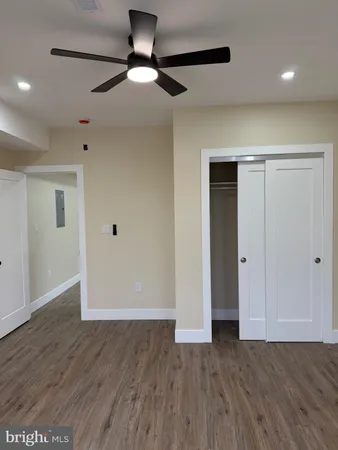 a view of an empty room with wooden floor and a ceiling fan