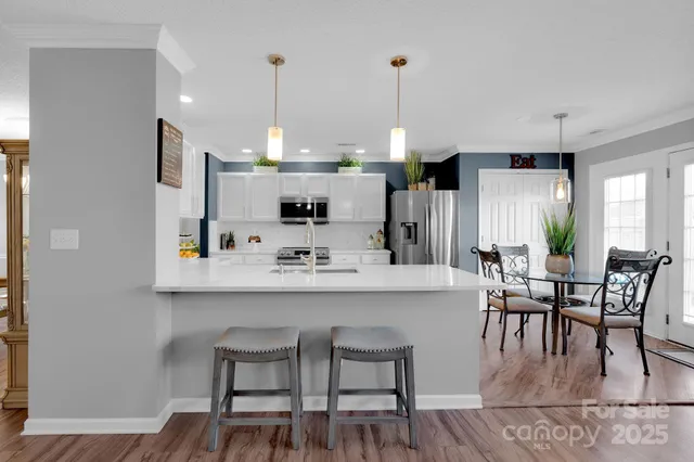 a kitchen with kitchen island a dining table chairs and white cabinets