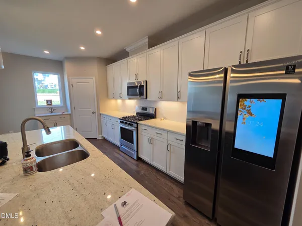 a kitchen with granite countertop kitchen island stainless steel appliances a sink a stove a refrigerator a microwave a sink and cabinets