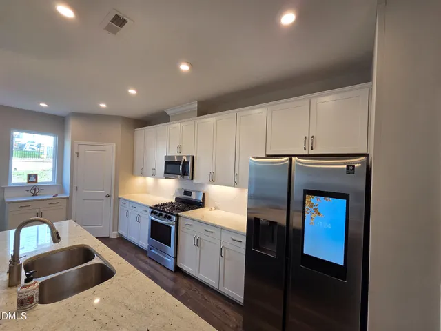 a kitchen with stainless steel appliances granite countertop a sink stove and refrigerator