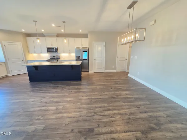 a large room with a kitchen island wooden floor and a chandelier