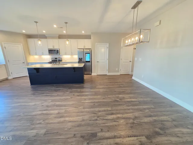 a large room with a kitchen island wooden floor and a chandelier