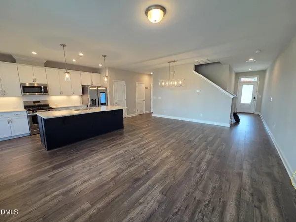 a view of kitchen with kitchen island wooden floors and stainless steel appliances