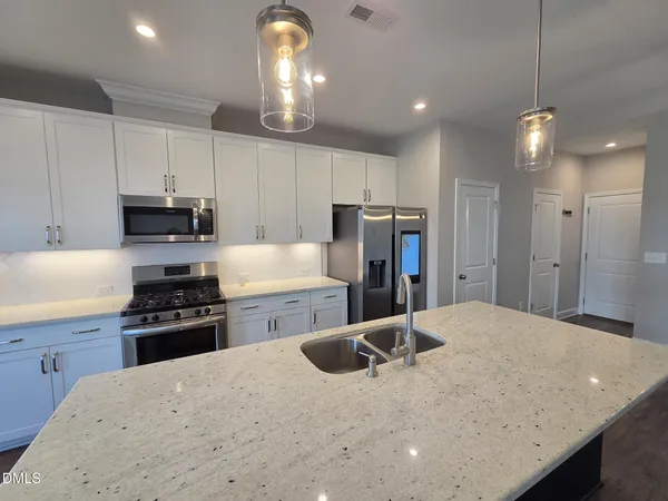 a kitchen with refrigerator a stove and a sink with wooden floor