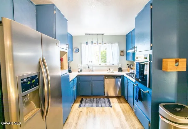 a kitchen with stainless steel appliances granite countertop a refrigerator a stove and a sink