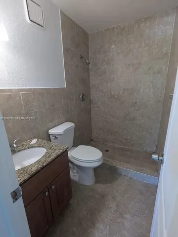 a bathroom with a granite countertop toilet a sink and a mirror