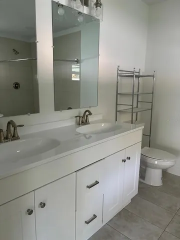 a bathroom with a double vanity sink toilet and mirror