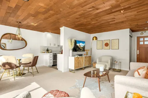a living room with furniture a flat screen tv and kitchen view