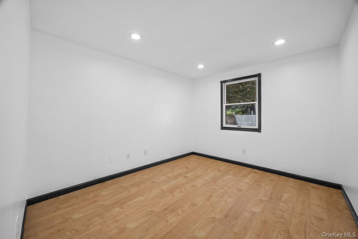 819 Canal Road Mount Sinai, NY 11766 - Photo 14 of 33 Room with light wood flooring, white walls, and a window with a dark frame