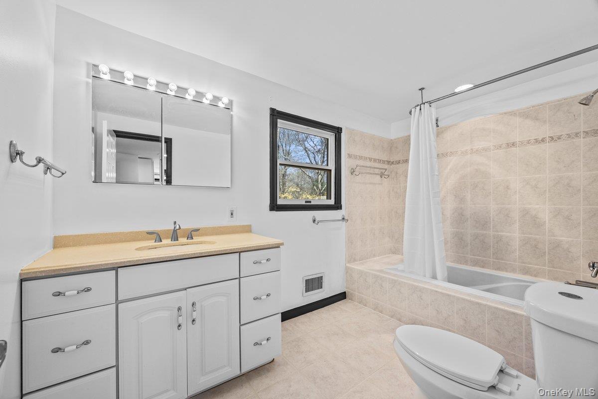 819 Canal Road Mount Sinai, NY 11766 - Photo 16 of 33 The bathroom features a vanity with a light-colored countertop and a mirror with integrated lighting