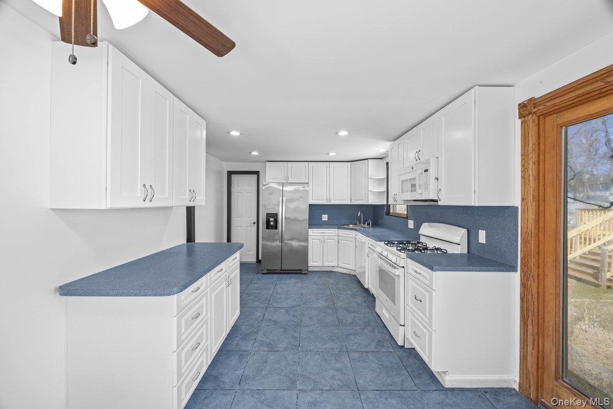 819 Canal Road Mount Sinai, NY 11766 - Photo 20 of 33 The kitchen features white cabinetry, blue countertops, and a white oven with a range