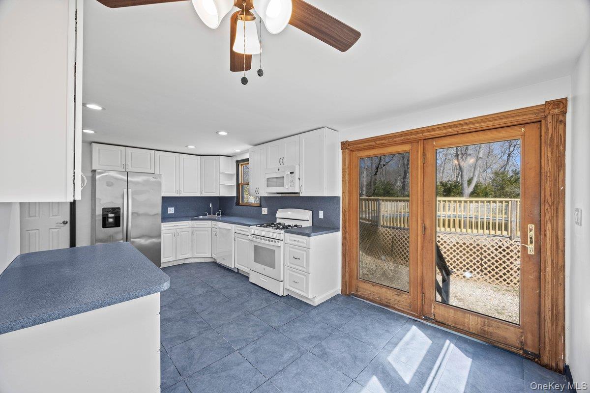 819 Canal Road Mount Sinai, NY 11766 - Photo 21 of 33 The kitchen features white cabinetry, stainless steel appliances, blue countertops, and tiled flooring