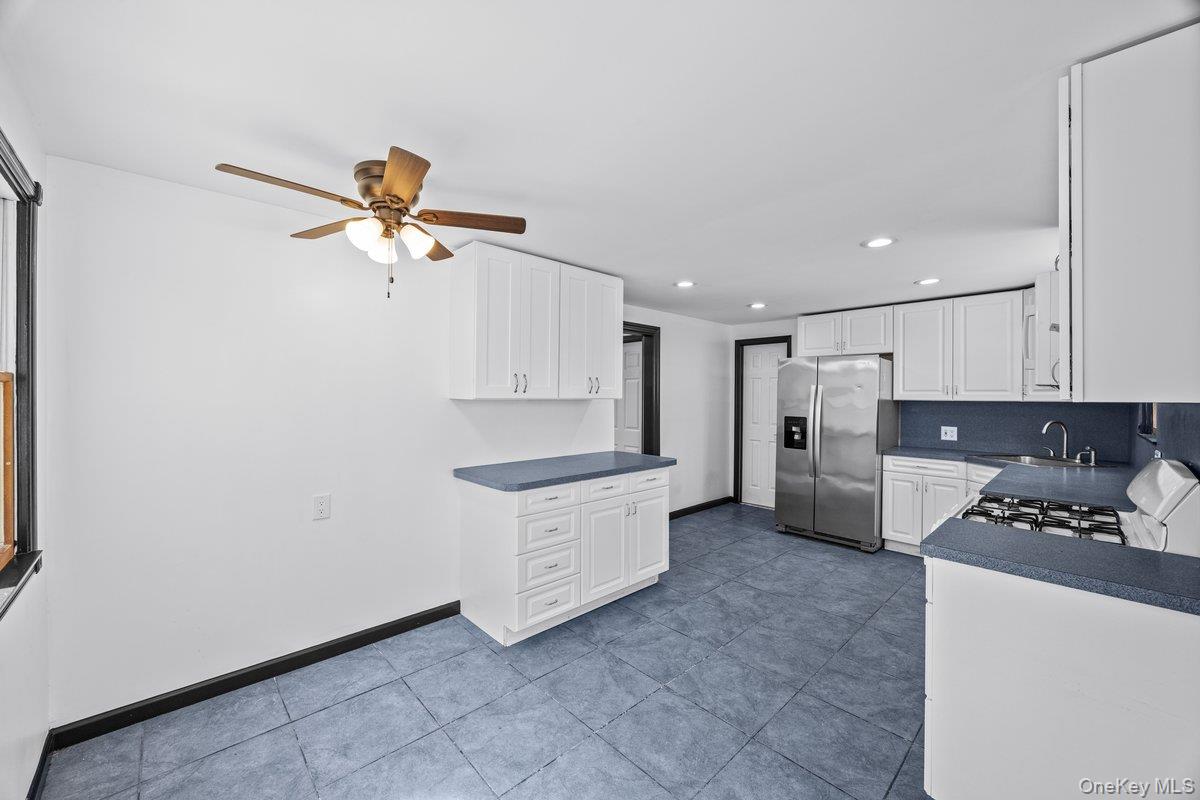 819 Canal Road Mount Sinai, NY 11766 - Photo 22 of 33 Kitchen featuring white cabinetry, blue countertops, blue tile flooring, and a stainless steel refrigerator
