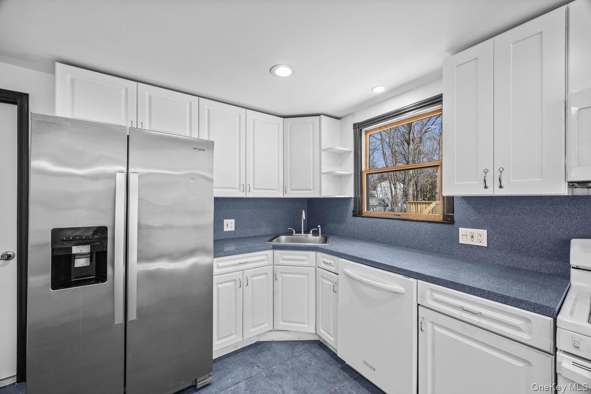 819 Canal Road Mount Sinai, NY 11766 - Photo 23 of 33 The kitchen features white cabinetry, blue countertops, and a stainless steel side-by-side refrigerator