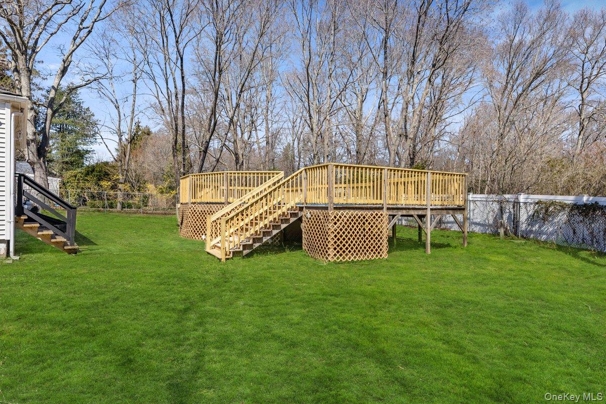 819 Canal Road Mount Sinai, NY 11766 - Photo 26 of 33 The property features a spacious yard with a large lawn and a wooden deck, complete with stairs and railings