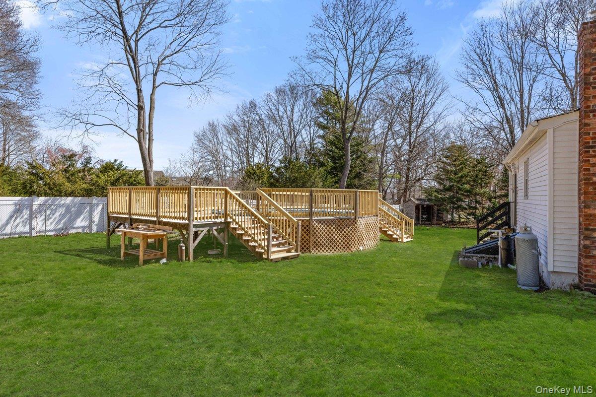819 Canal Road Mount Sinai, NY 11766 - Photo 27 of 33 Expansive backyard featuring a well-maintained lawn, a spacious wooden deck with railings, and a white picket fence