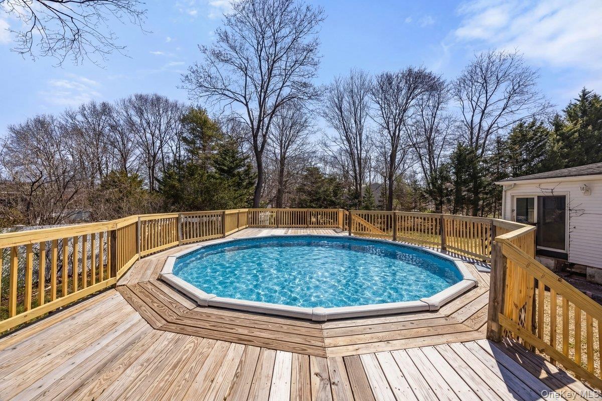819 Canal Road Mount Sinai, NY 11766 - Photo 28 of 33 The property features an outdoor swimming pool surrounded by a wooden deck with railing
