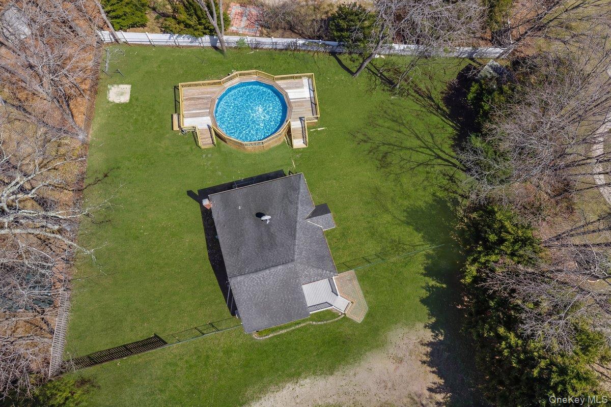 819 Canal Road Mount Sinai, NY 11766 - Photo 32 of 33 An aerial view of the property showcasing a private pool with a surrounding deck, a well-maintained lawn, and a fenced area