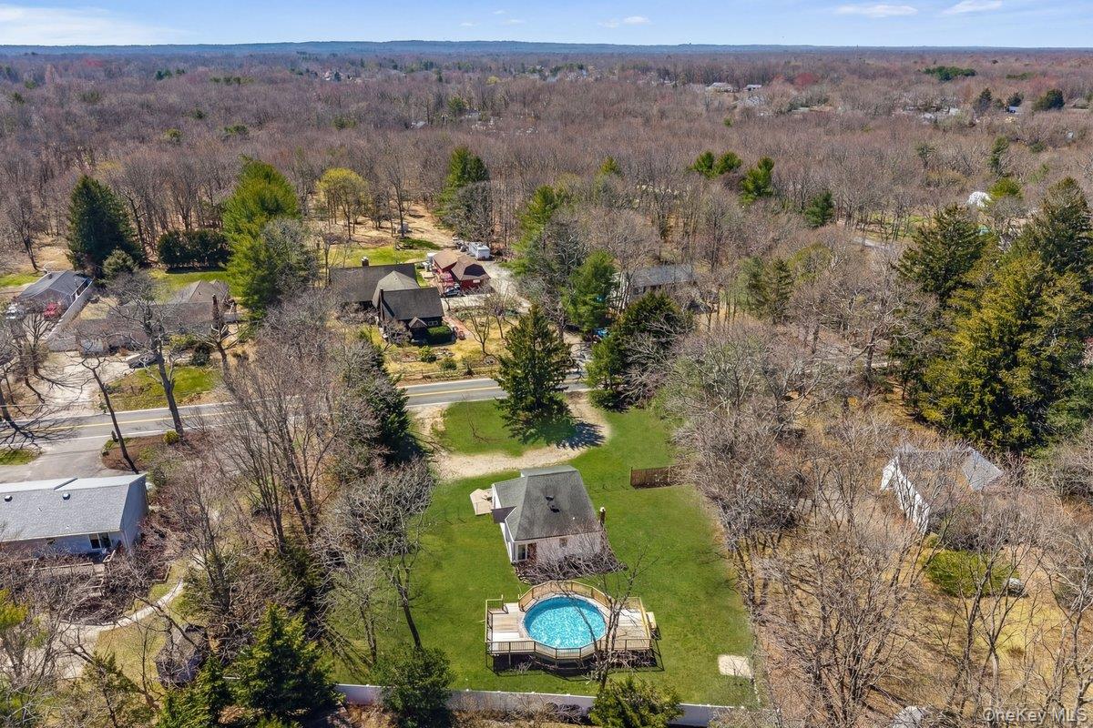 819 Canal Road Mount Sinai, NY 11766 - Photo 33 of 33 Aerial view showcasing the property with a blue above-ground pool, surrounded by a green lawn and mature trees