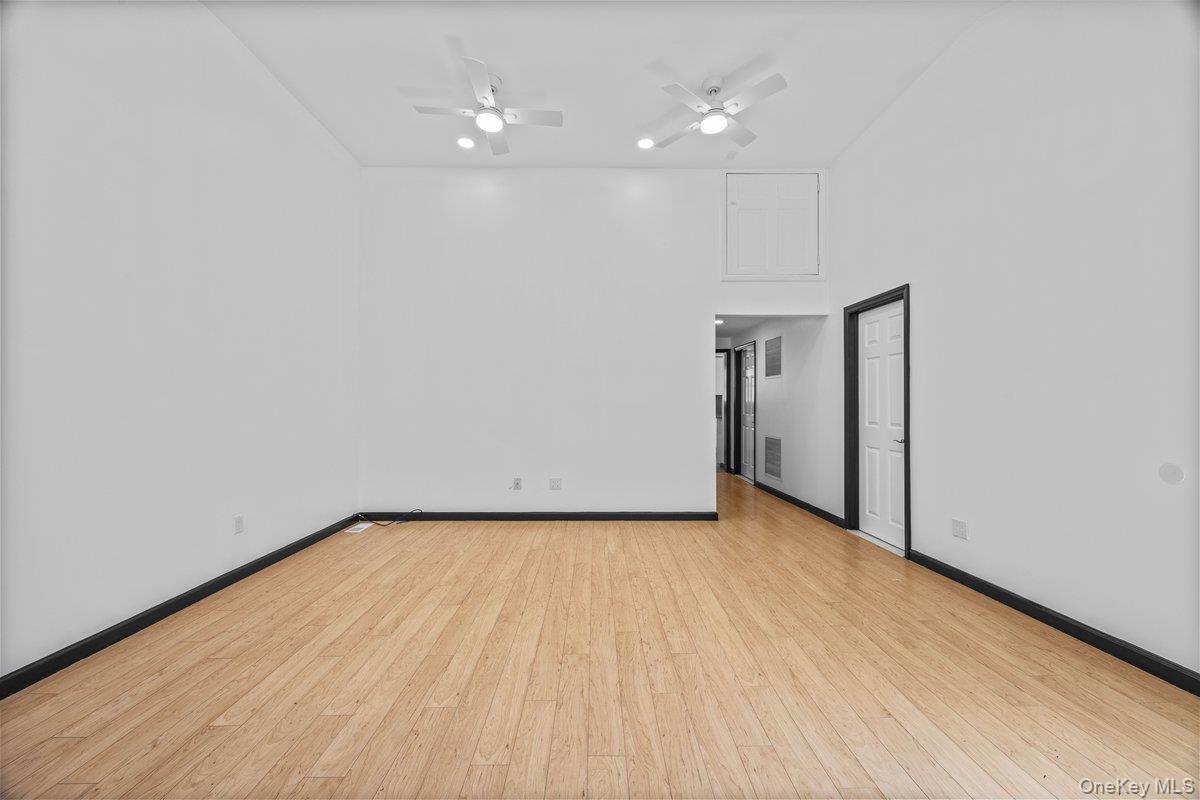 819 Canal Road Mount Sinai, NY 11766 - Photo 7 of 33 Spacious room featuring light-toned hardwood flooring, white walls, and two ceiling fans with integrated lighting