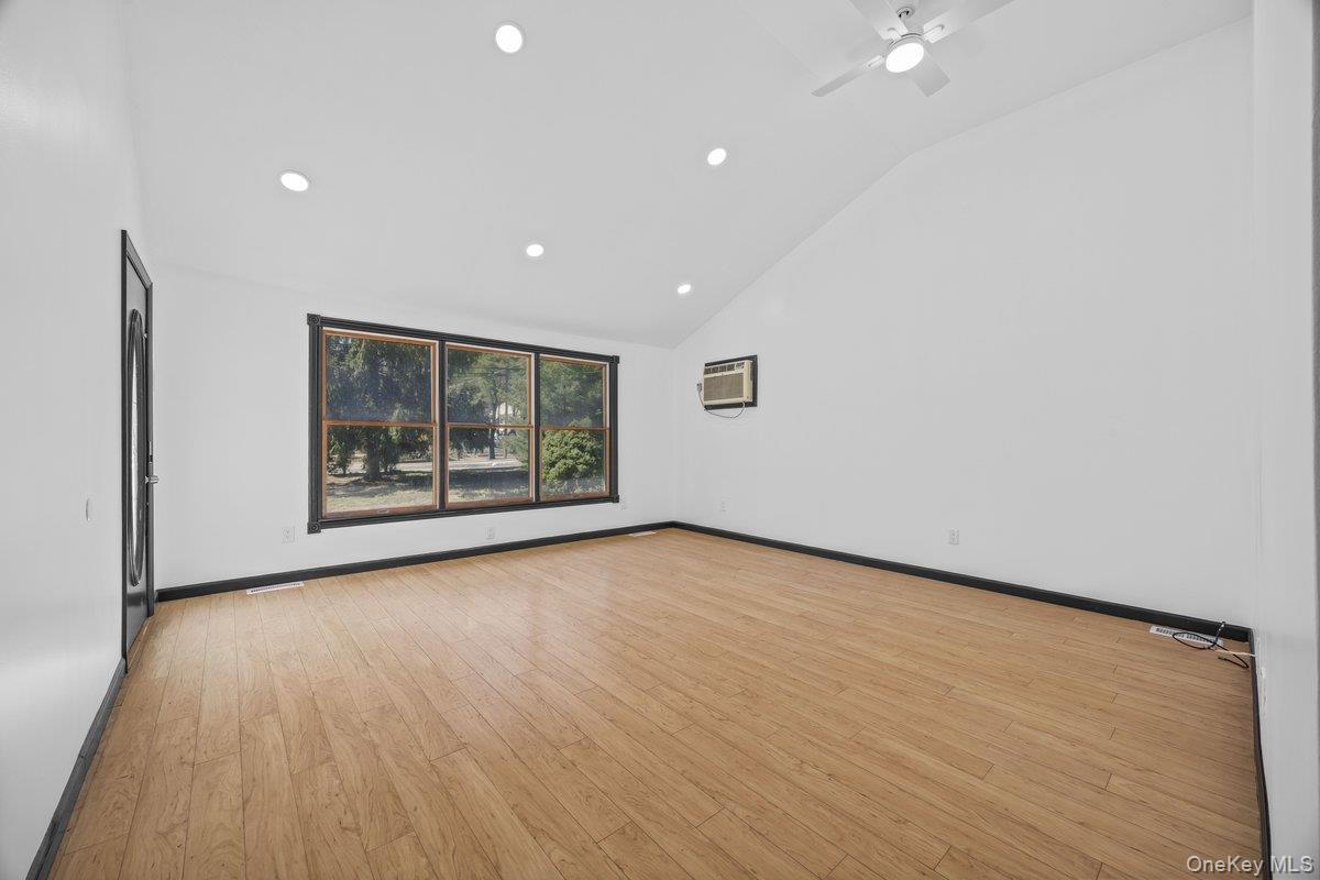 819 Canal Road Mount Sinai, NY 11766 - Photo 9 of 33 This room features light-toned wood flooring, a window offering views of trees, and a ceiling fan