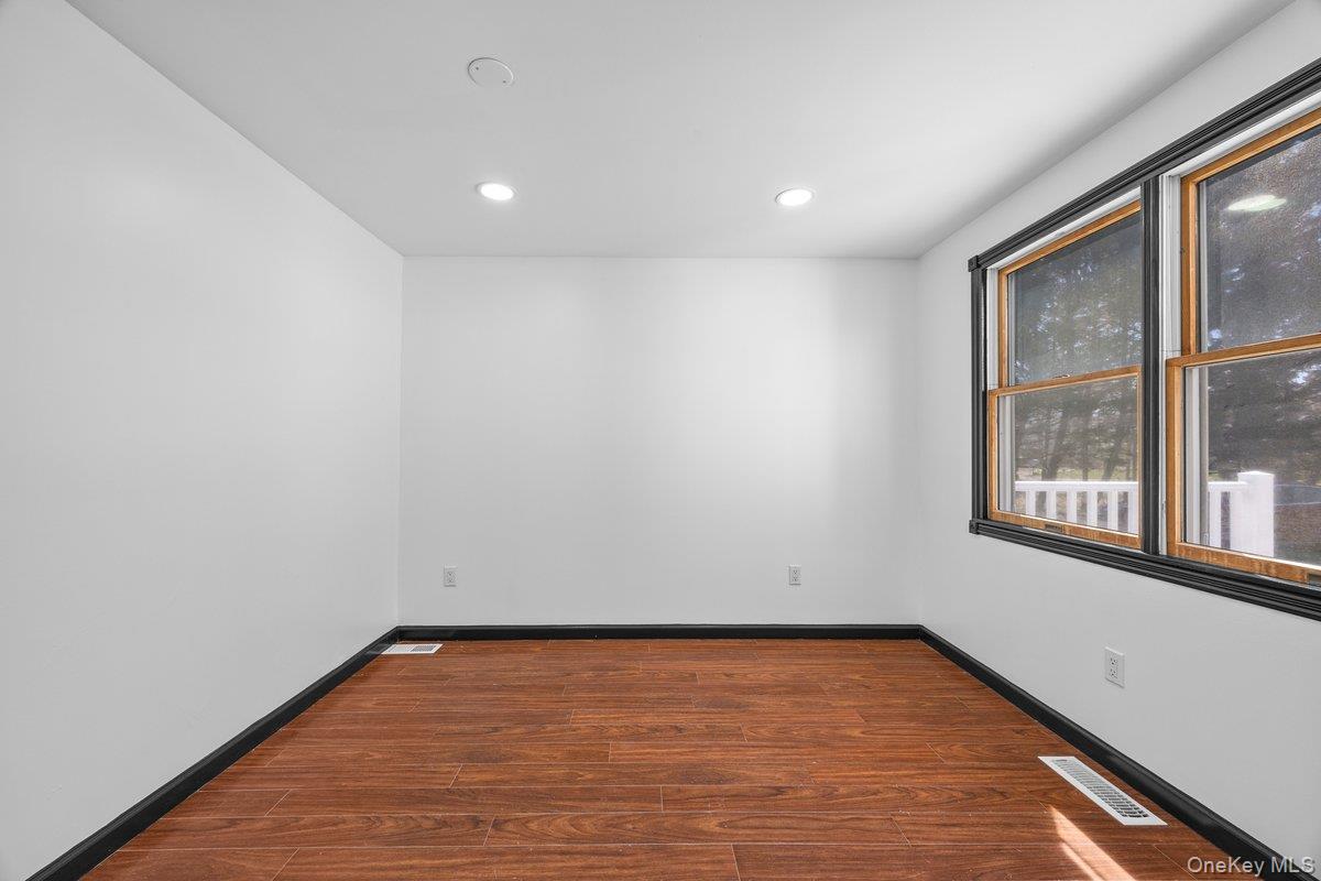 819 Canal Road Mount Sinai, NY 11766 - Photo 10 of 33 This room features hardwood flooring, white walls, recessed lighting, and windows with dark trim, offering natural light