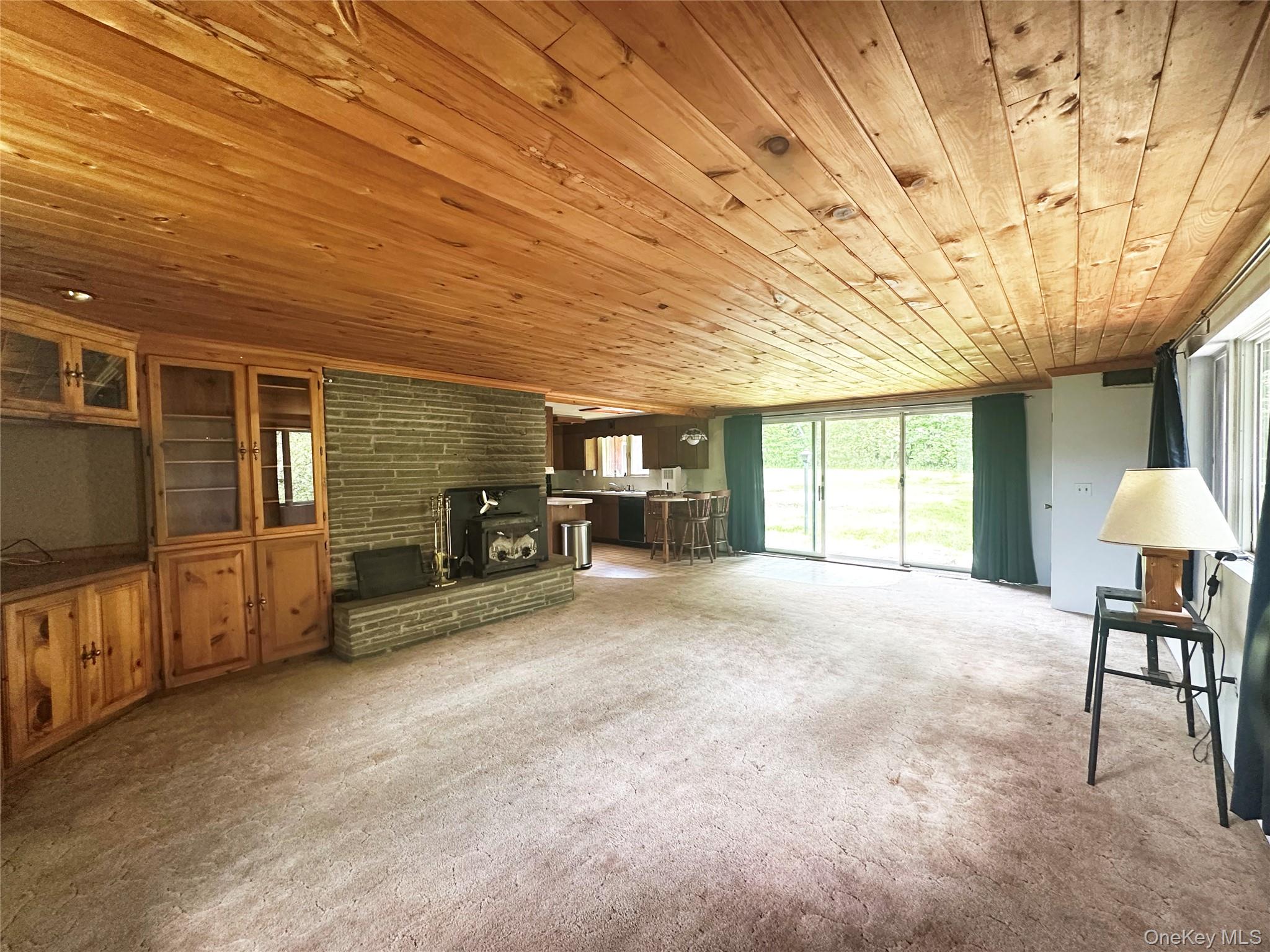 818 Methol Road Roscoe, NY 12776 - Photo 24 of 39 Wide-angle view of the open-concept living and dining area highlighting the rustic wood ceilings, fireplace centerpiece, and expansive layout.