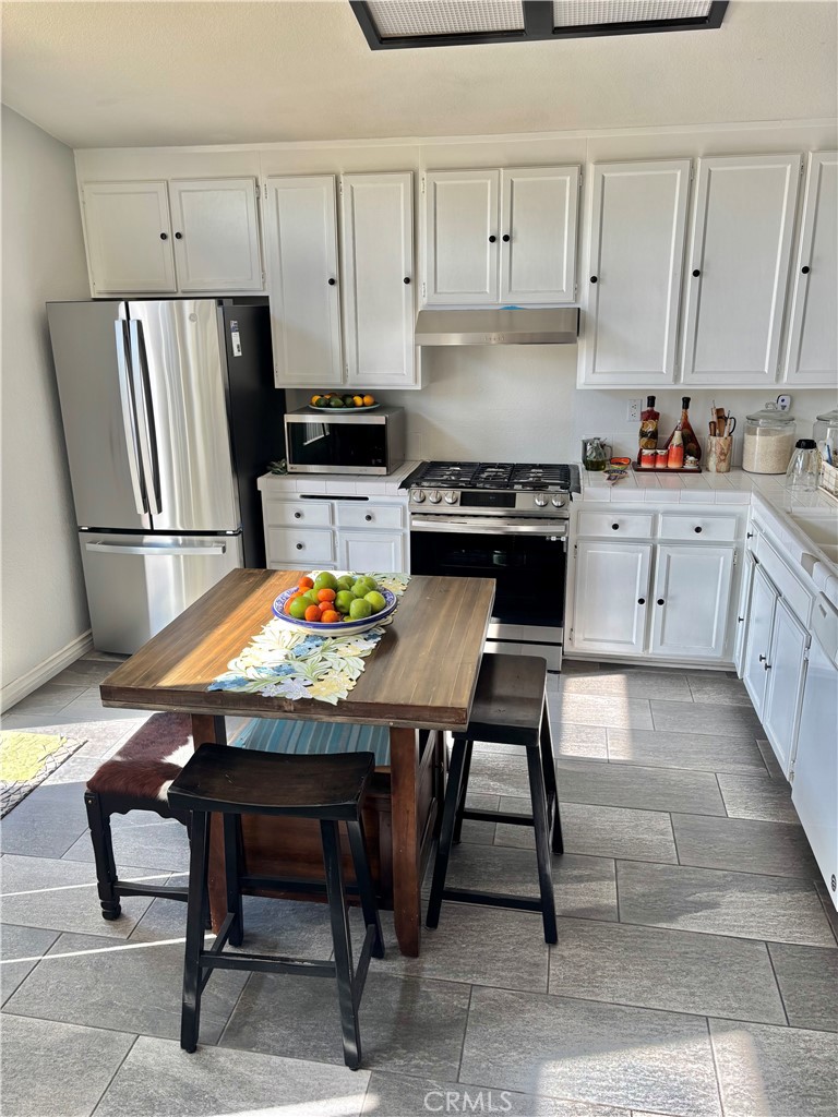 2830-2830 Chuckwagon Road Palmdale, CA 93550 - Photo 10 of 11 a kitchen with a refrigerator a stove a sink dishwasher and white cabinets with wooden floor