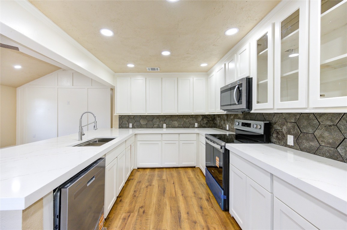 235 6th Street Trinity, TX 75862 - Photo 7 of 29 a kitchen with kitchen island granite countertop a sink stove oven and white cabinets with wooden floor