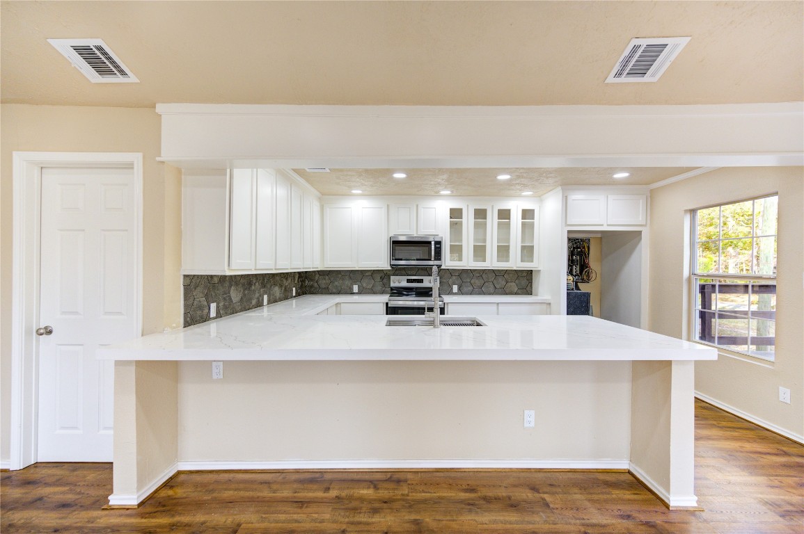 235 6th Street Trinity, TX 75862 - Photo 10 of 29 a large white kitchen with kitchen island a sink a stove and wooden floors
