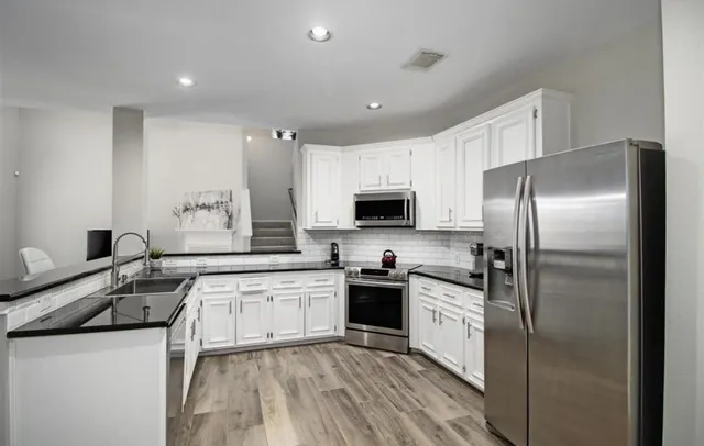 a kitchen with a sink a refrigerator and white cabinets