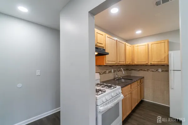 a kitchen with stainless steel appliances granite countertop a stove a sink and a refrigerator with wooden floor