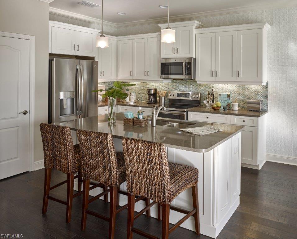 2295 Sawyers Hill Road, Unit 1007 Naples, FL 34120 - Photo 2 of 12 a kitchen with stainless steel appliances granite countertop a white table and chairs